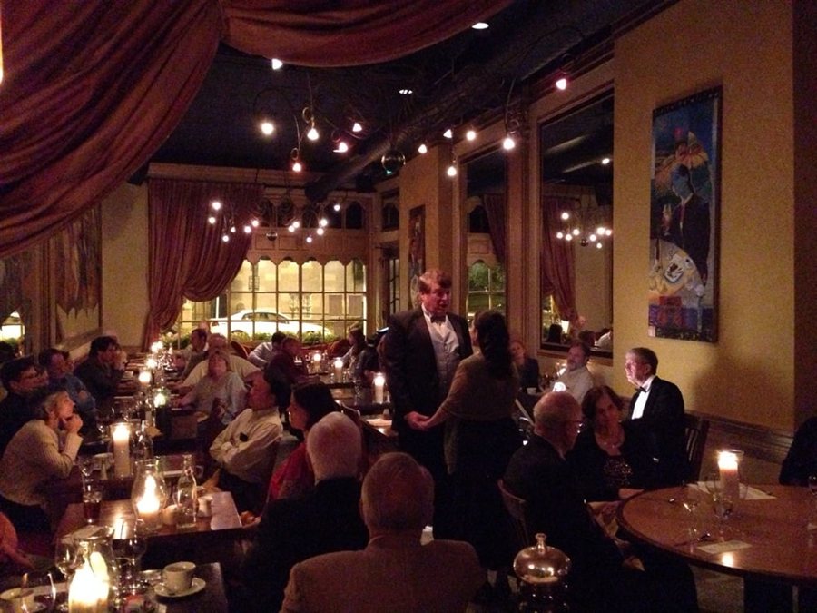 Guests dining beneath the chandeliers and red curtains at Sotto Sopra