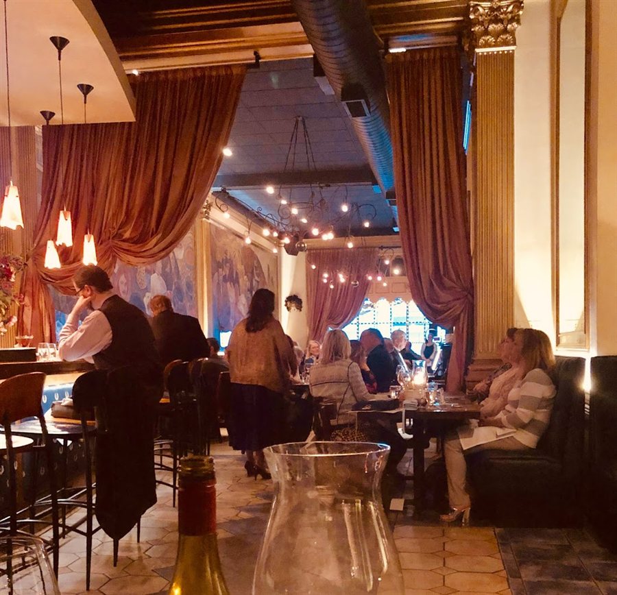 Warmly lit Sotto Sopra dining room framed by tall curtains